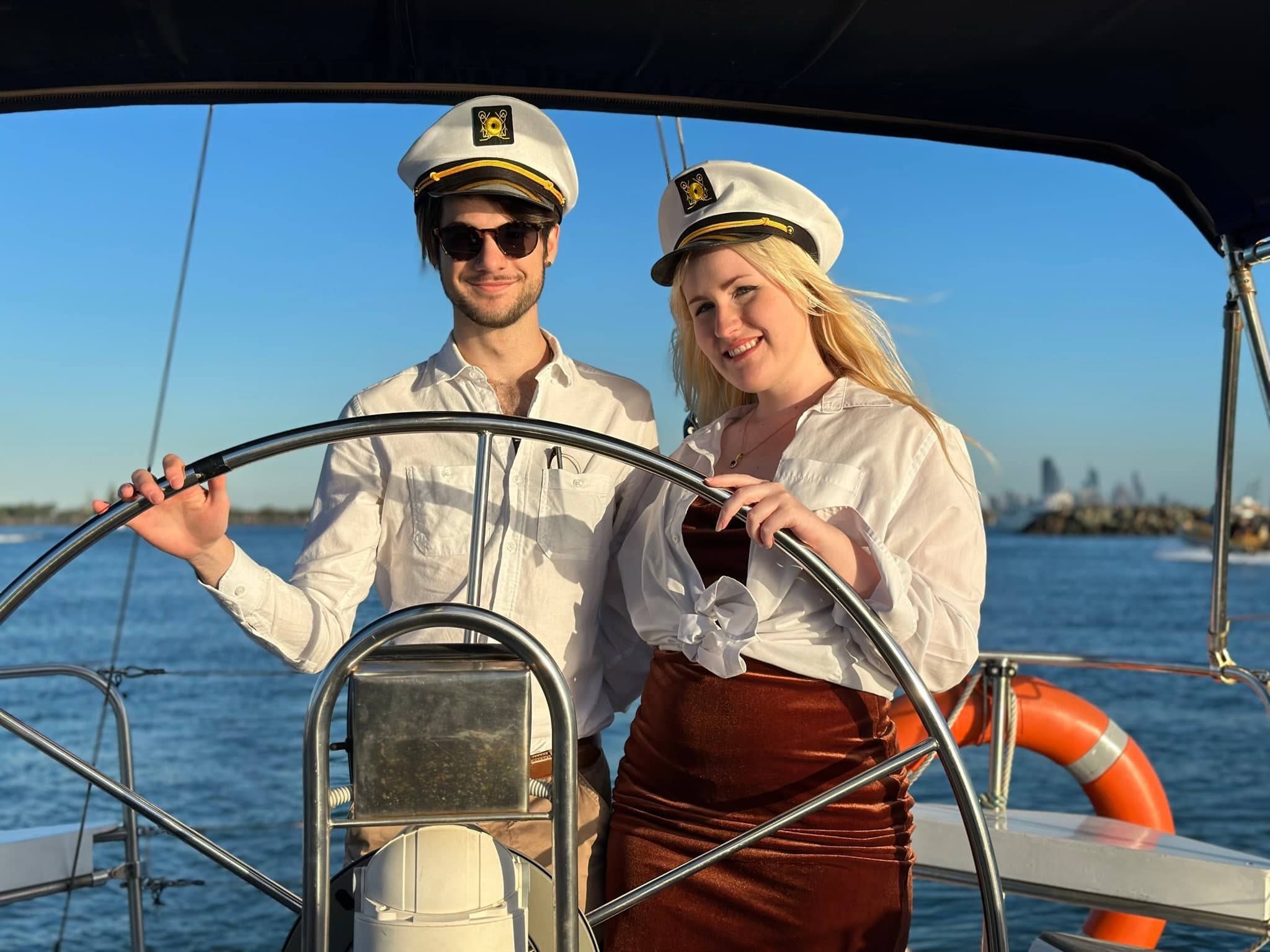 Couple steering sailboat helm under clear sky, nautical vibe