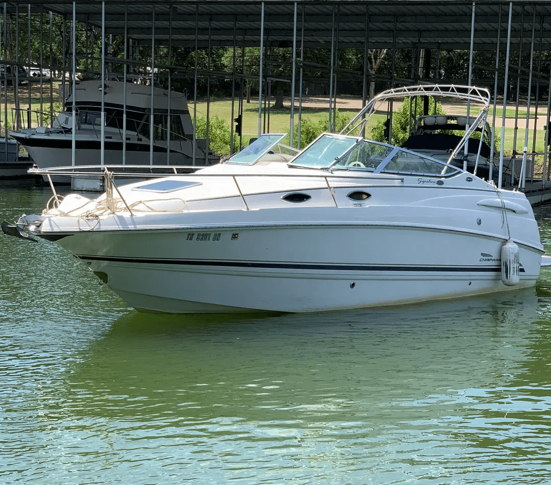 White cabin cruiser moored at covered marina on green lake water