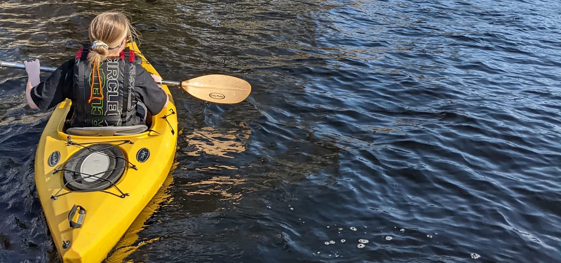 Solo kayaker paddling on calm lake near forested shore