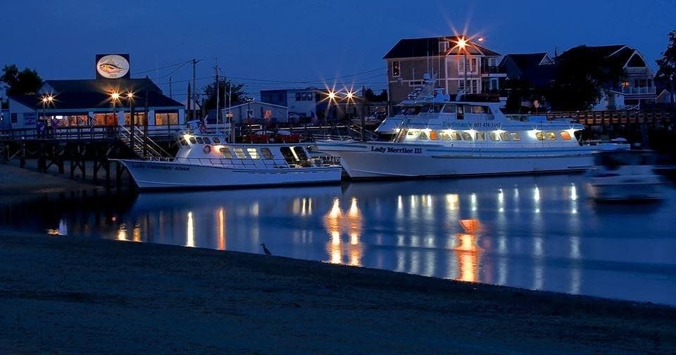 Night marina with docked charter boats reflecting on harbor water