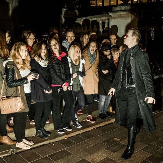 Nighttime ghost tour guide addressing crowd outside Liverpool landmark