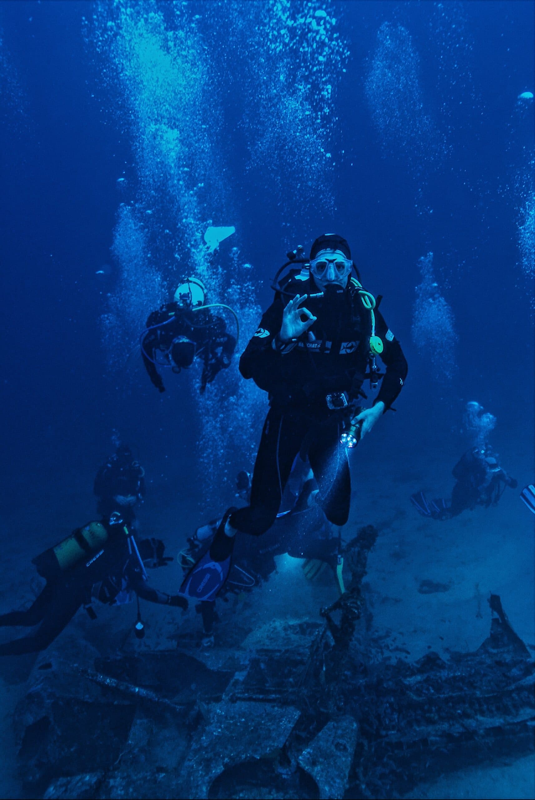 Scuba divers exploring underwater wreck site in deep blue ocean