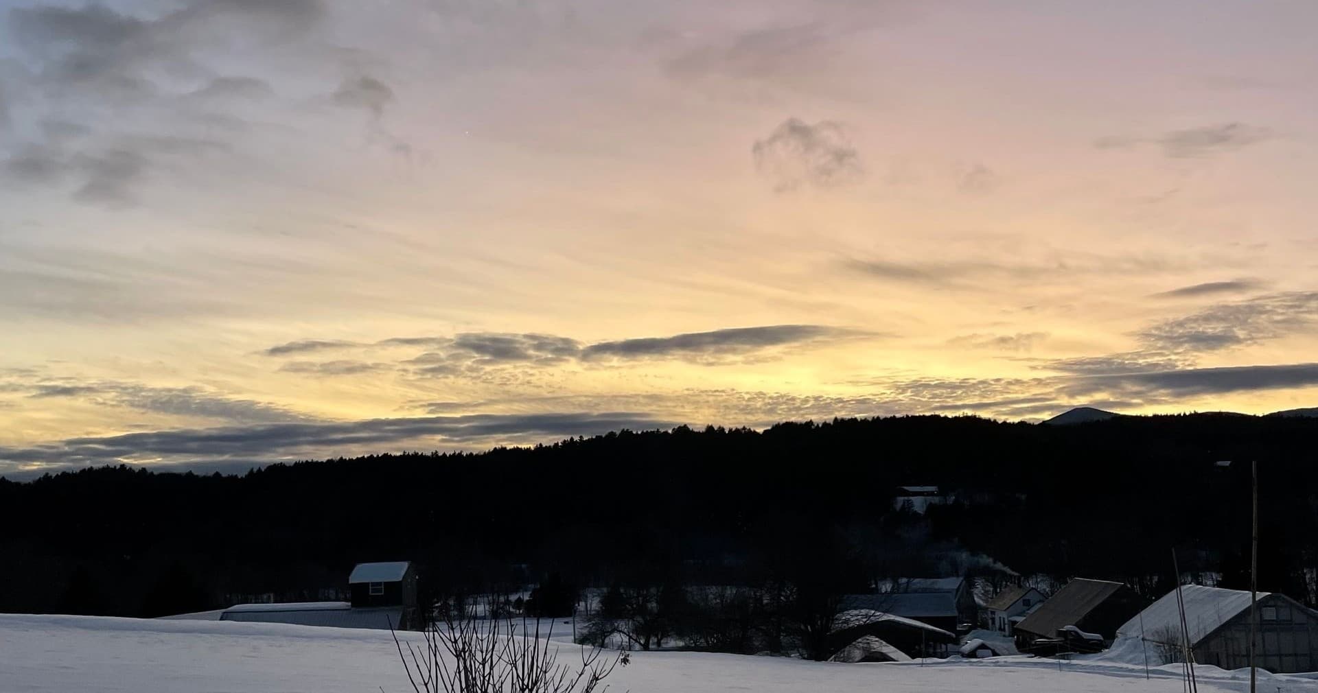 Sunrise silhouette over snowy rural hills and rooftops