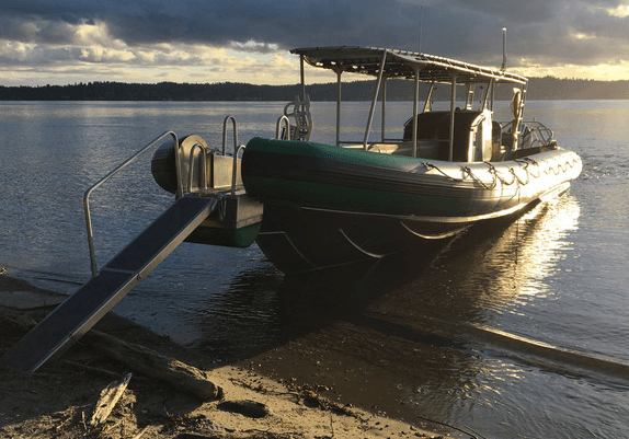 Small expedition boat moored at sunset on calm coastal shore