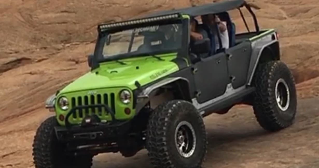 Green Jeep Wrangler climbing Moab slickrock, guided trail ride