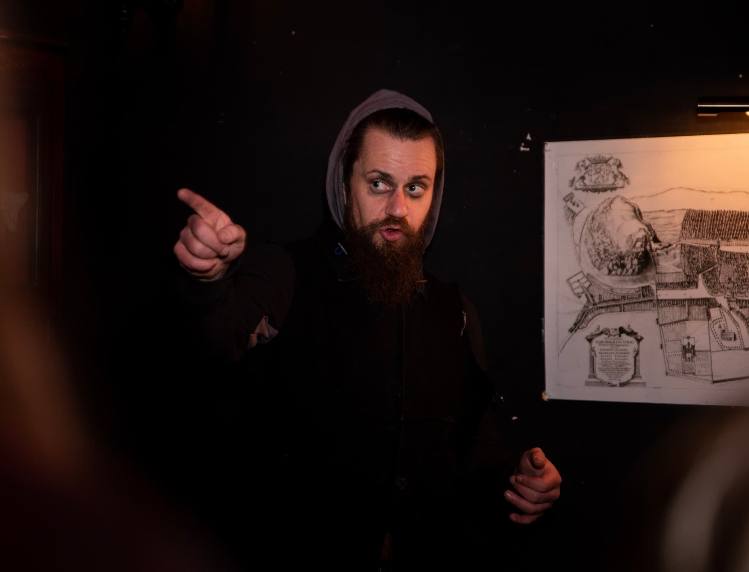 Tour guide pointing at map in dim historic pub during Edinburgh tour