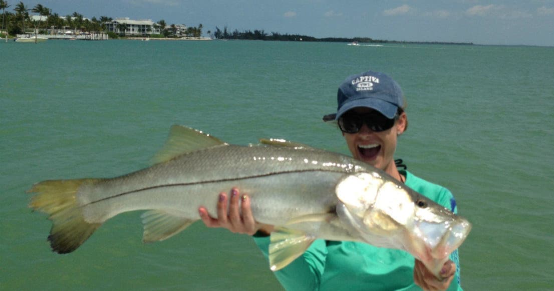 Angler holding large snook on boat in shallow coastal waters