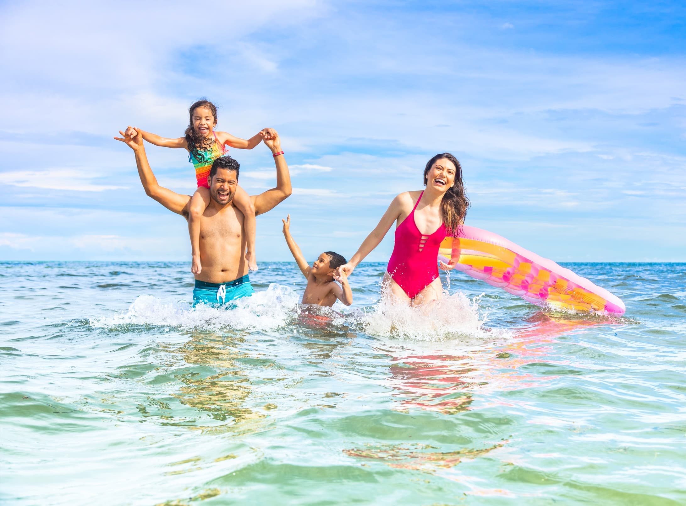 Family playing in shallow clear ocean water with inflatable