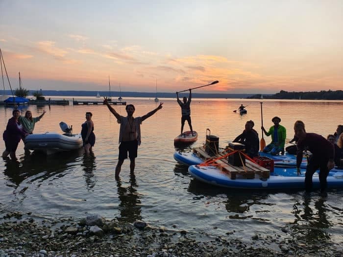 Group launching paddleboards and boats at lakeside sunset