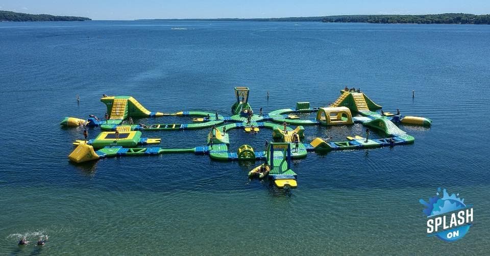 Aerial inflatable water park on clear lake with guests playing