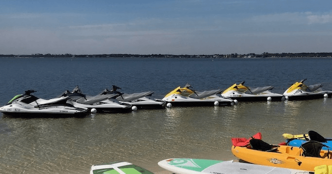 Row of jet skis lined on calm bay water at shore