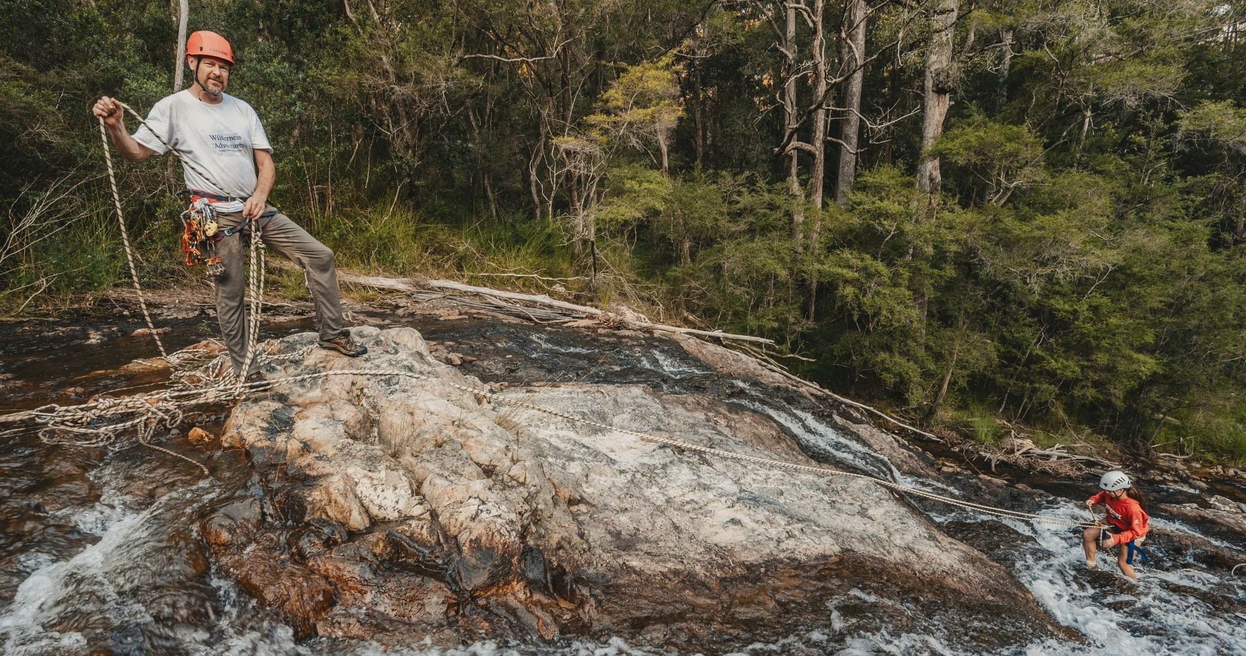 Guide rappelling on riverside rock during canyoning trip