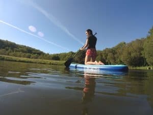 Stand-up paddleboarding on calm lake with scenic shoreline