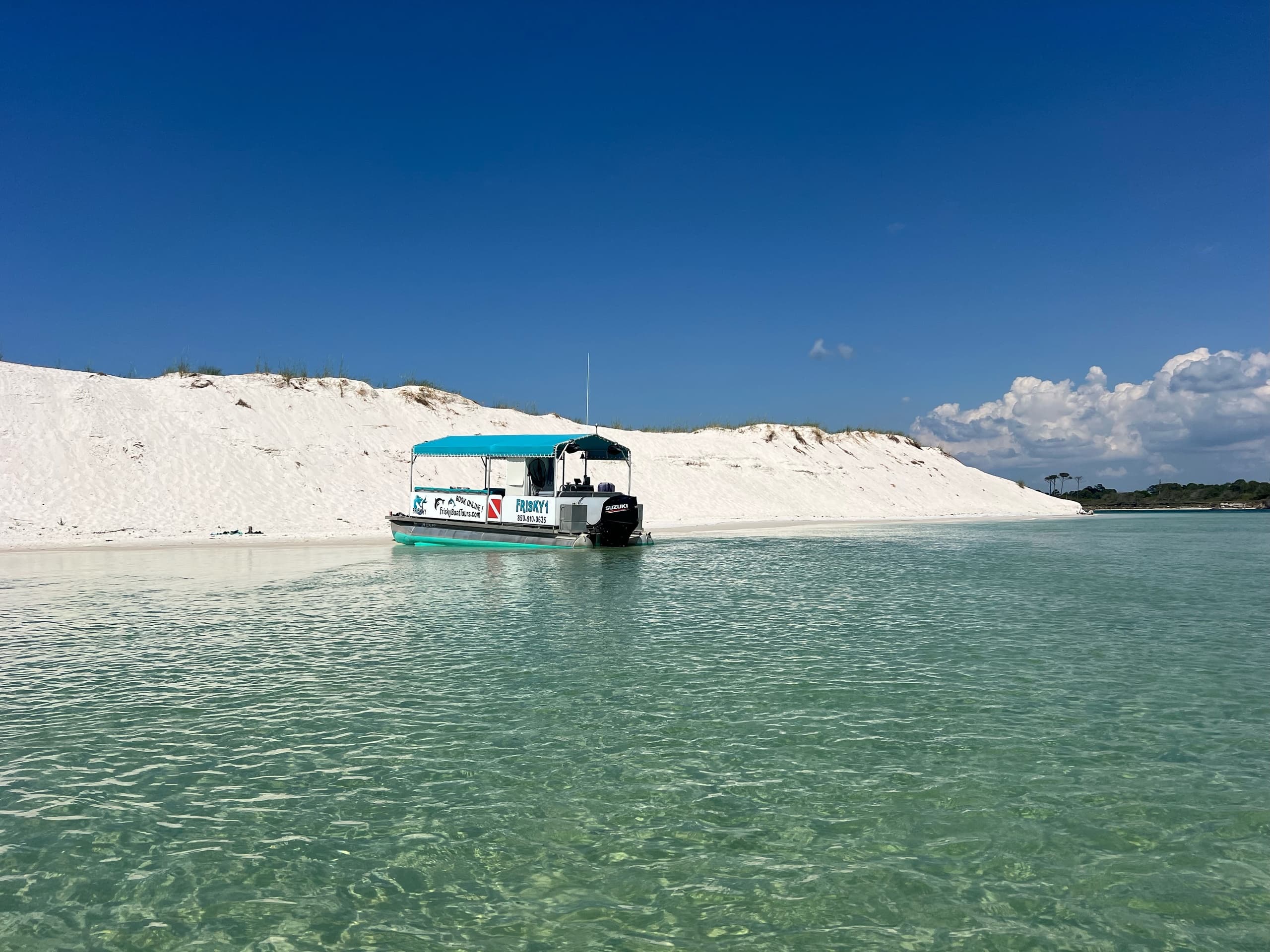 Small boat anchored in turquoise shallow bay near sandbar