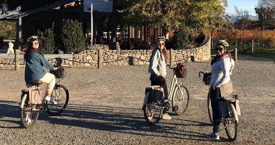 Three cyclists riding through winery courtyard on guided bike tour