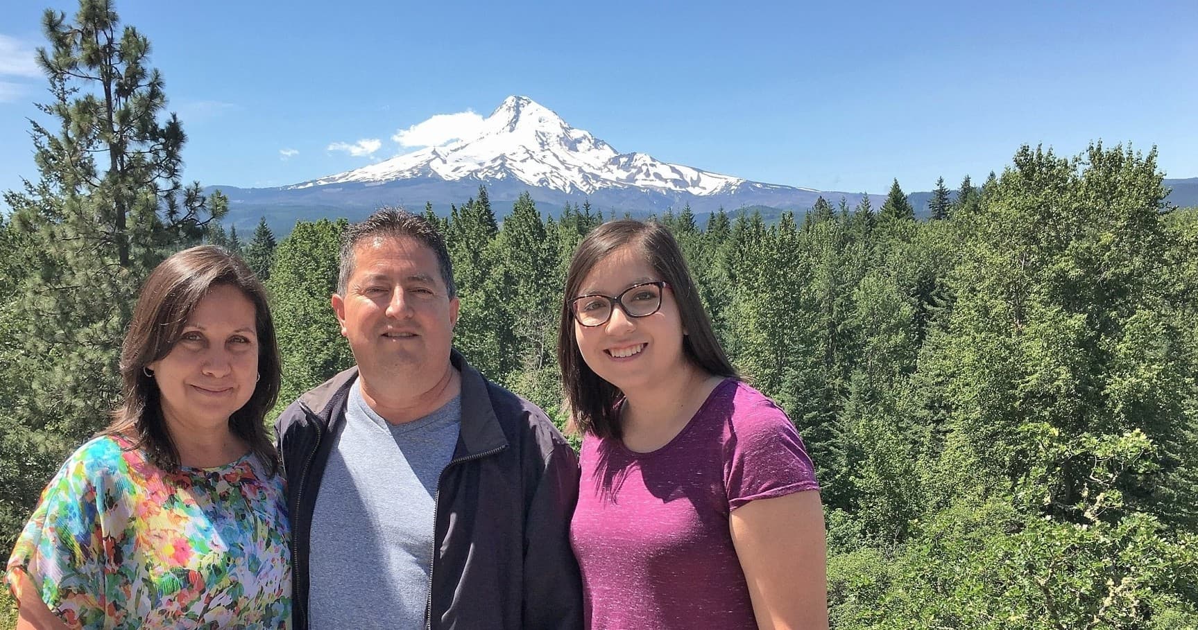 Family posing before snowcapped Mount Hood, forest viewpoint