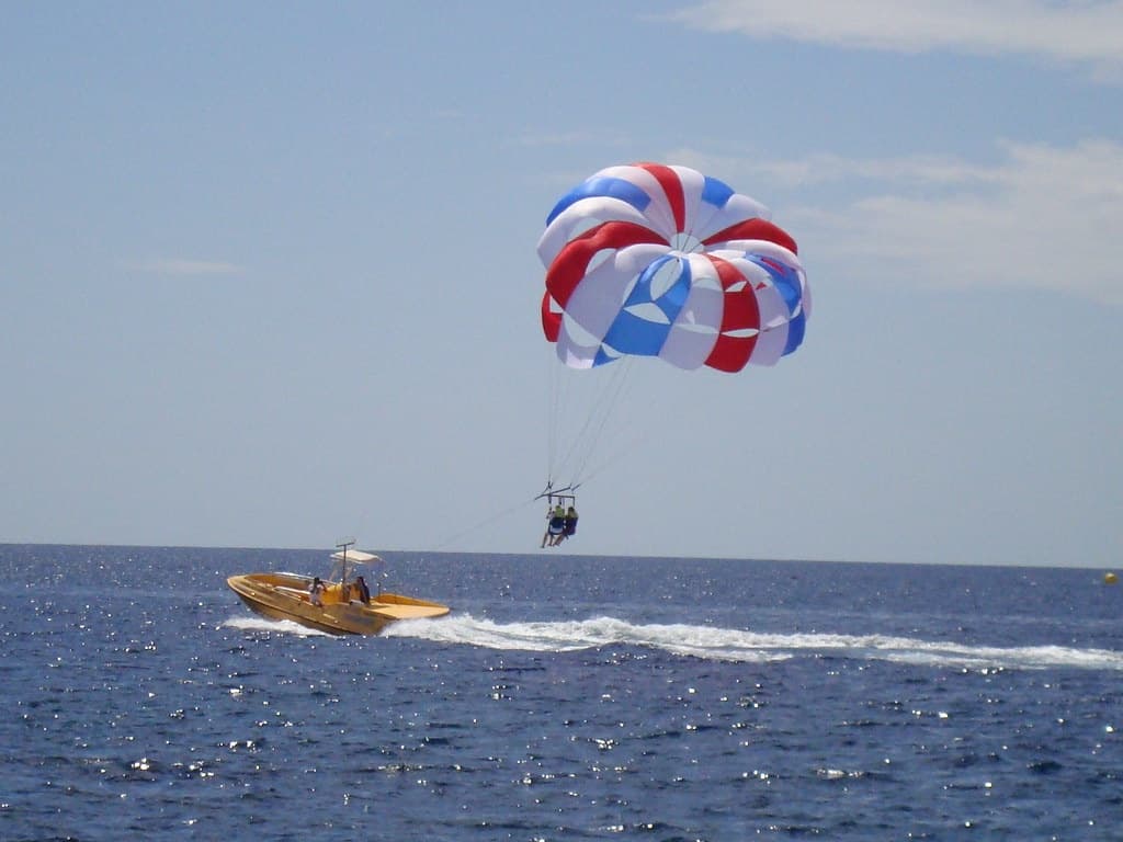 Parasailing over open ocean with speedboat, aerial adventure