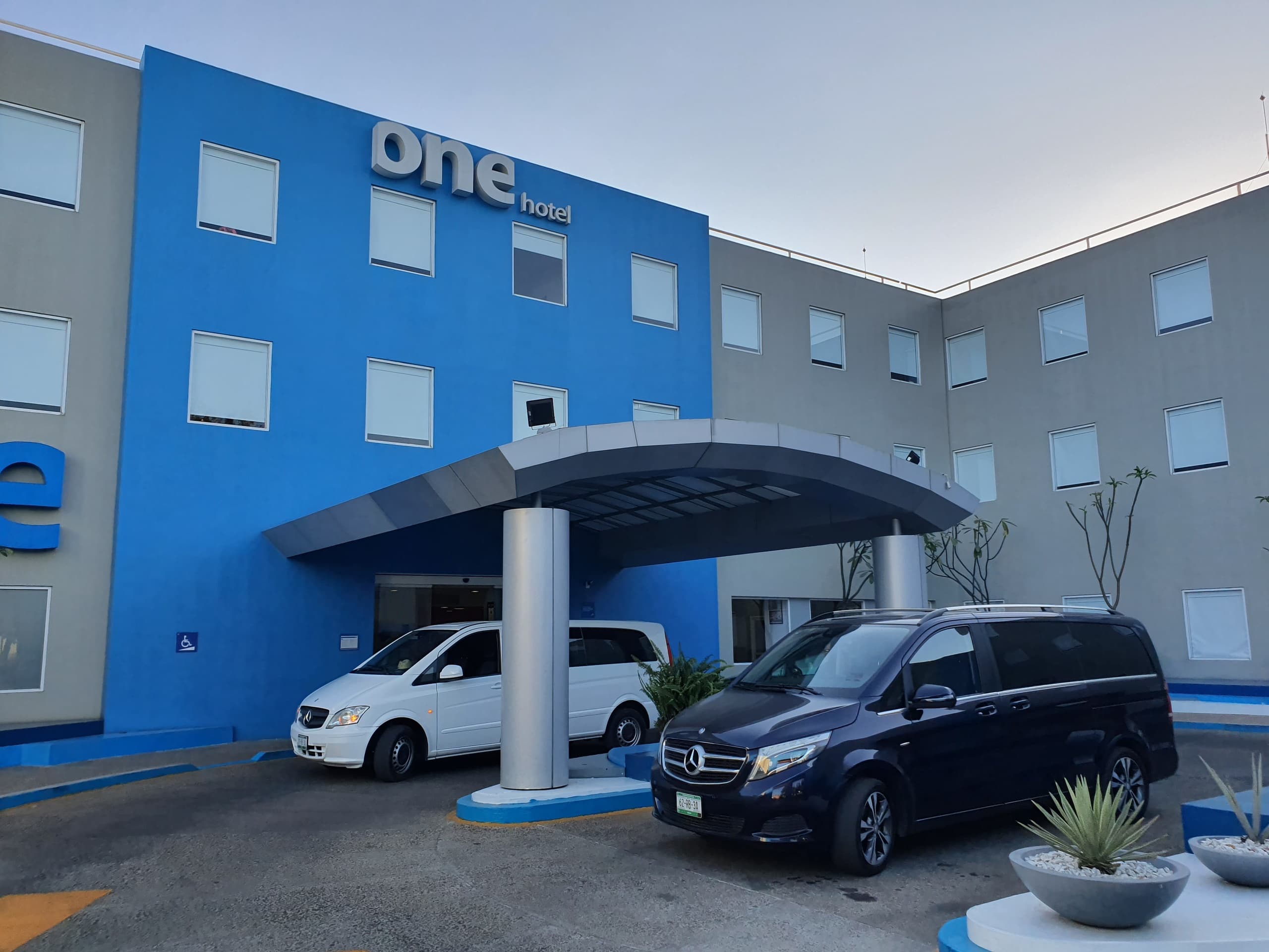 Hotel entrance with shuttle vans parked, traveler pickup area