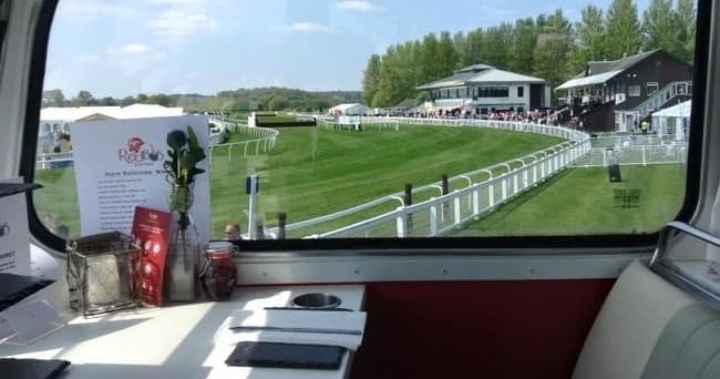 Spectators view horse racetrack from vintage bus window