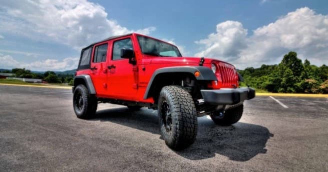 Red Jeep Wrangler on open road under blue sky for scenic drives