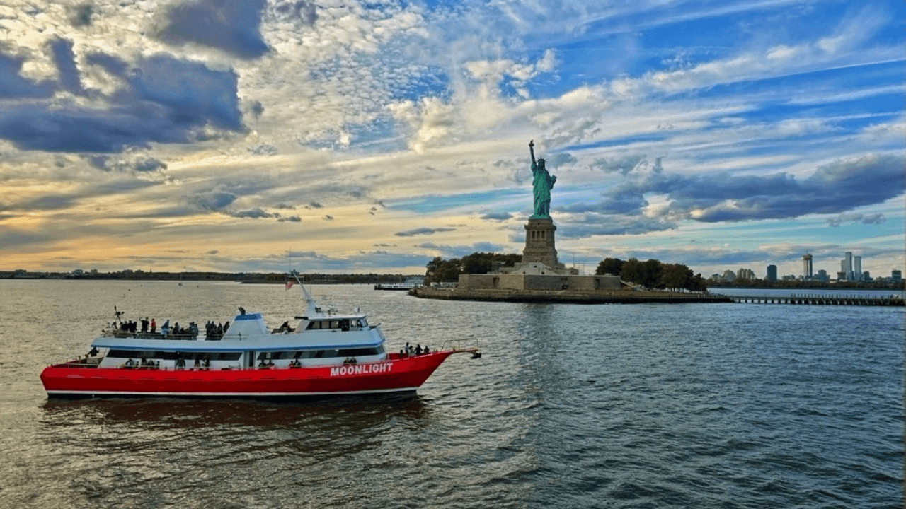Sightseeing ferry passing Statue of Liberty at sunset, NYC