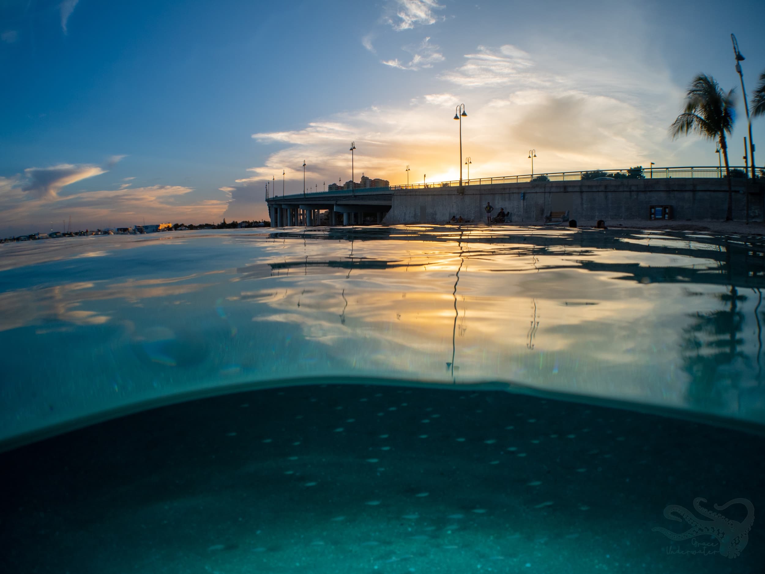 Split-view sunset over pier and clear ocean for scuba trips
