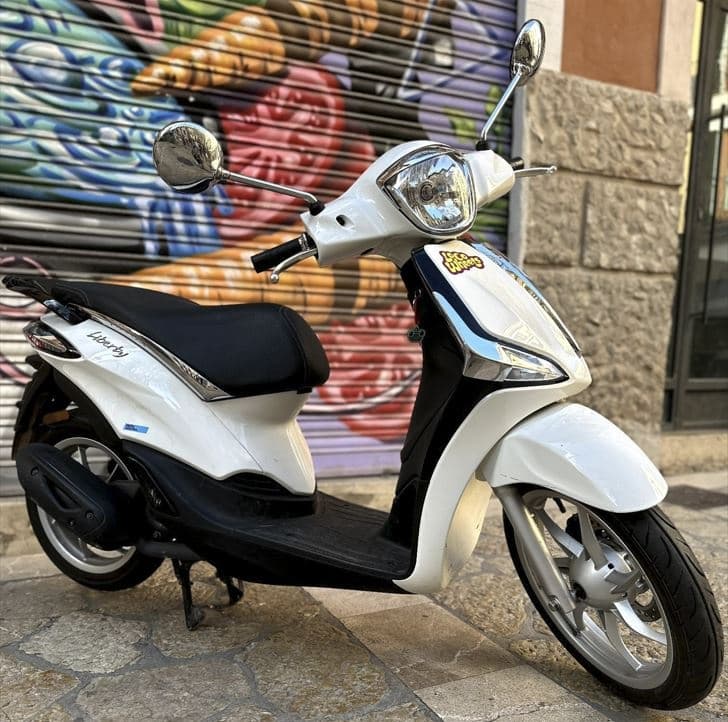 White scooter parked by graffiti shutter on urban stone street