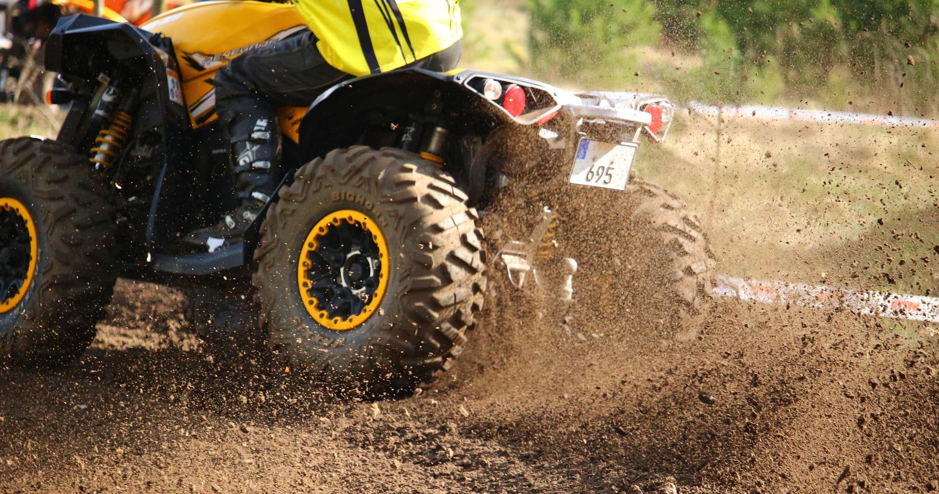 Close-up ATV rear kicking mud on trail, muddy off-road ride in woods