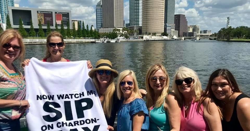 Friends sipping wine on Tampa riverboat with skyline views