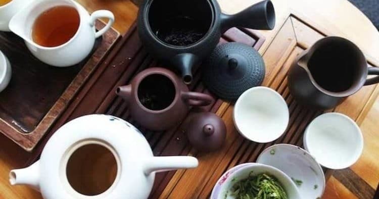 Assorted teapots and cups laid out for traditional tea tasting