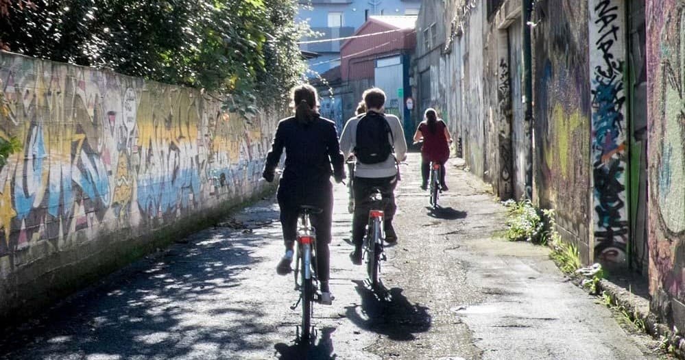 Cyclists pedaling through graffiti alley on Bilbao bike tour