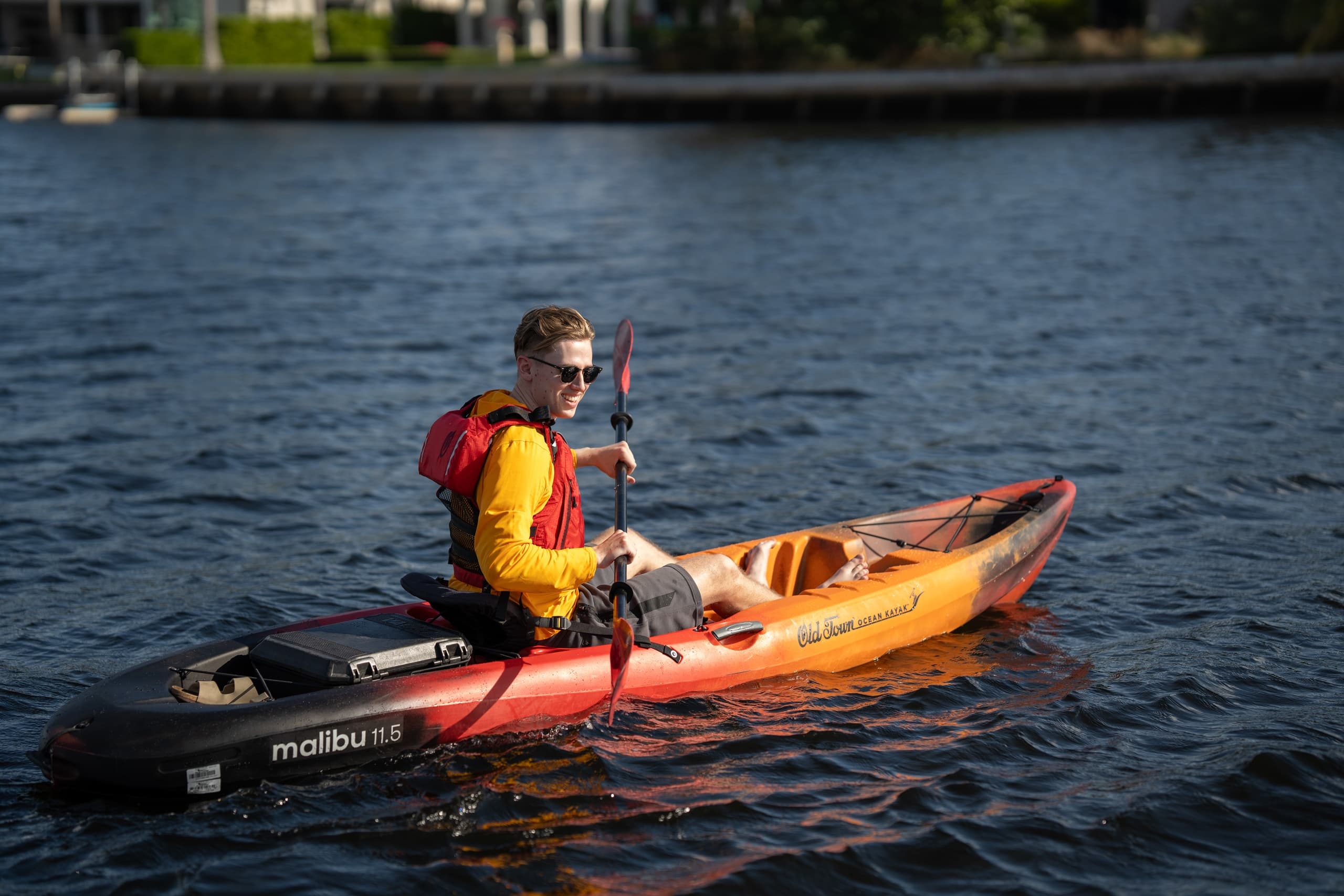 Solo paddler in bright jacket kayaking on urban waterfront