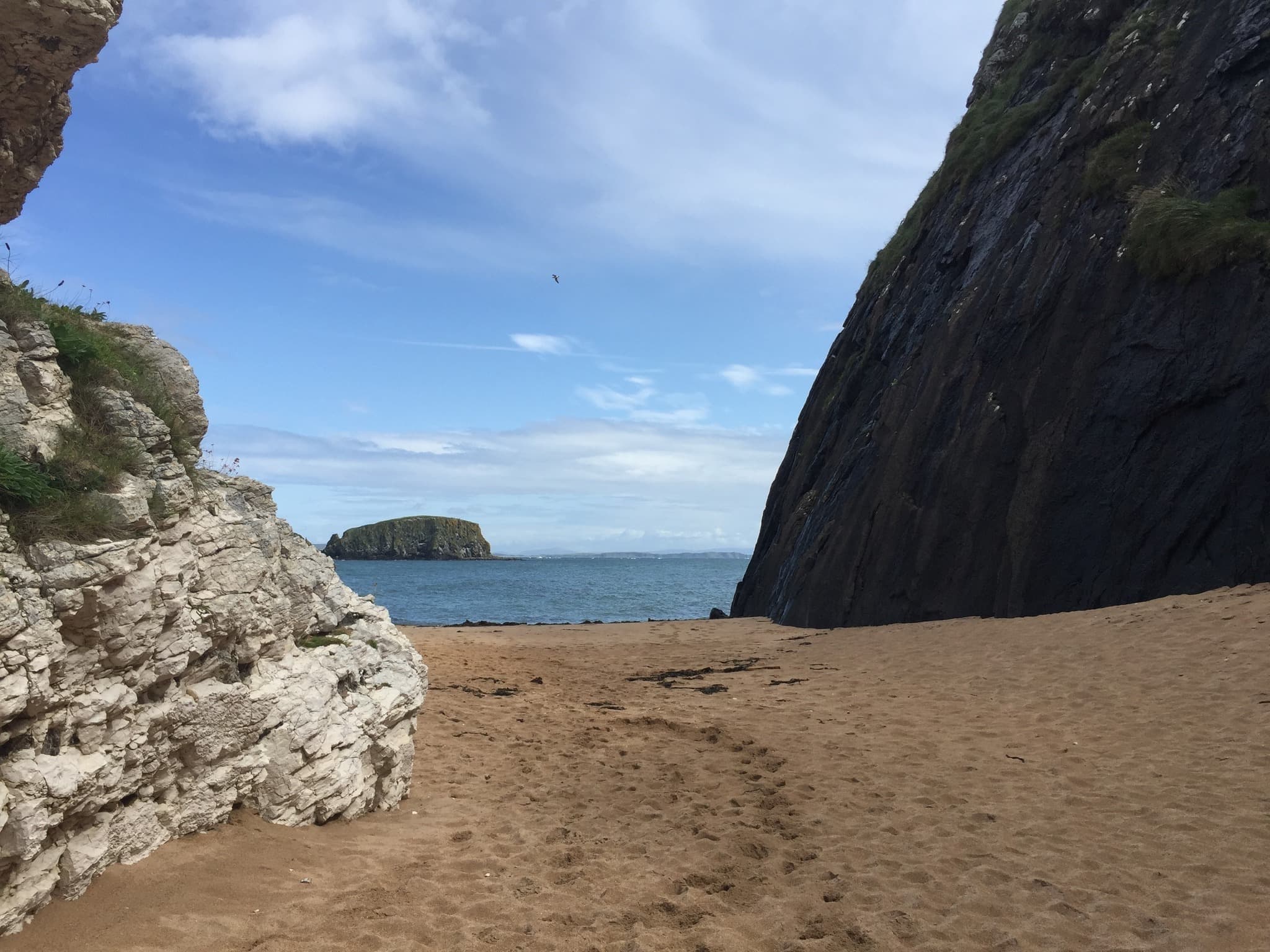 Sandy secluded cove framed by steep cliffs opening to ocean
