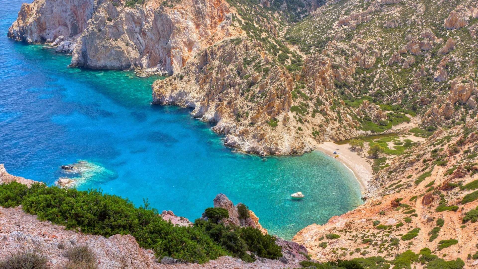Aerial view of secluded rocky cove with emerald blue sea
