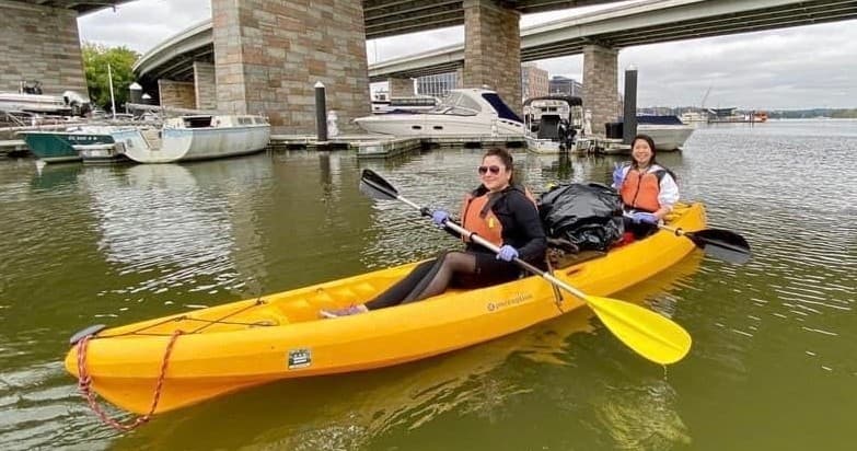 Pair kayaking under city bridge by marina in calm water