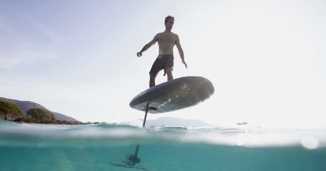 Person riding a hydrofoil board over clear ocean near shore