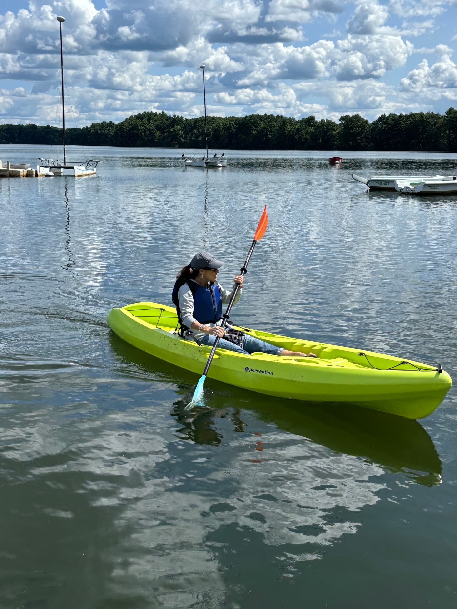 Solo kayaker paddling on calm lake near marina, summer