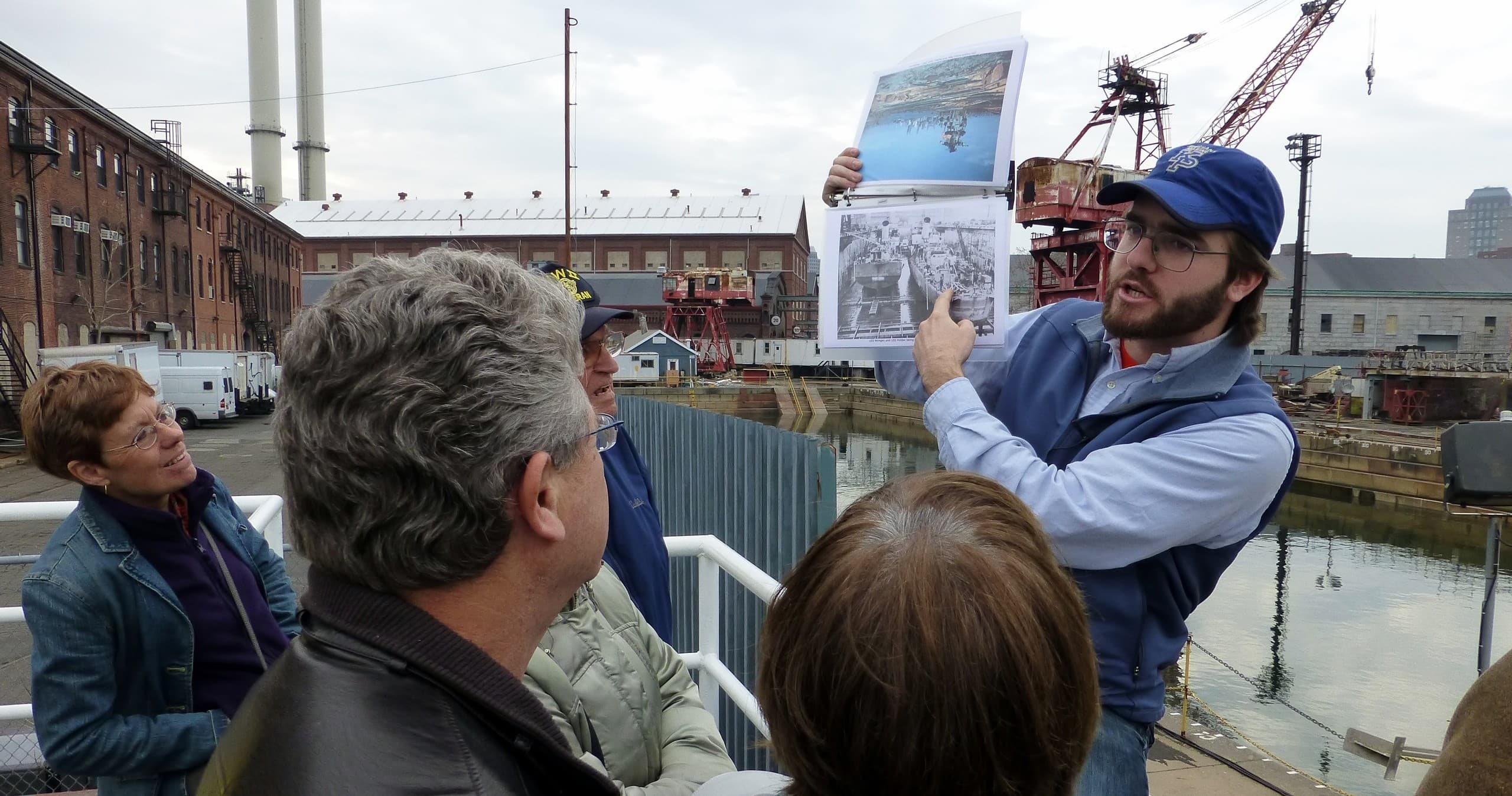 Tour guide showing maps to group by industrial waterfront dock