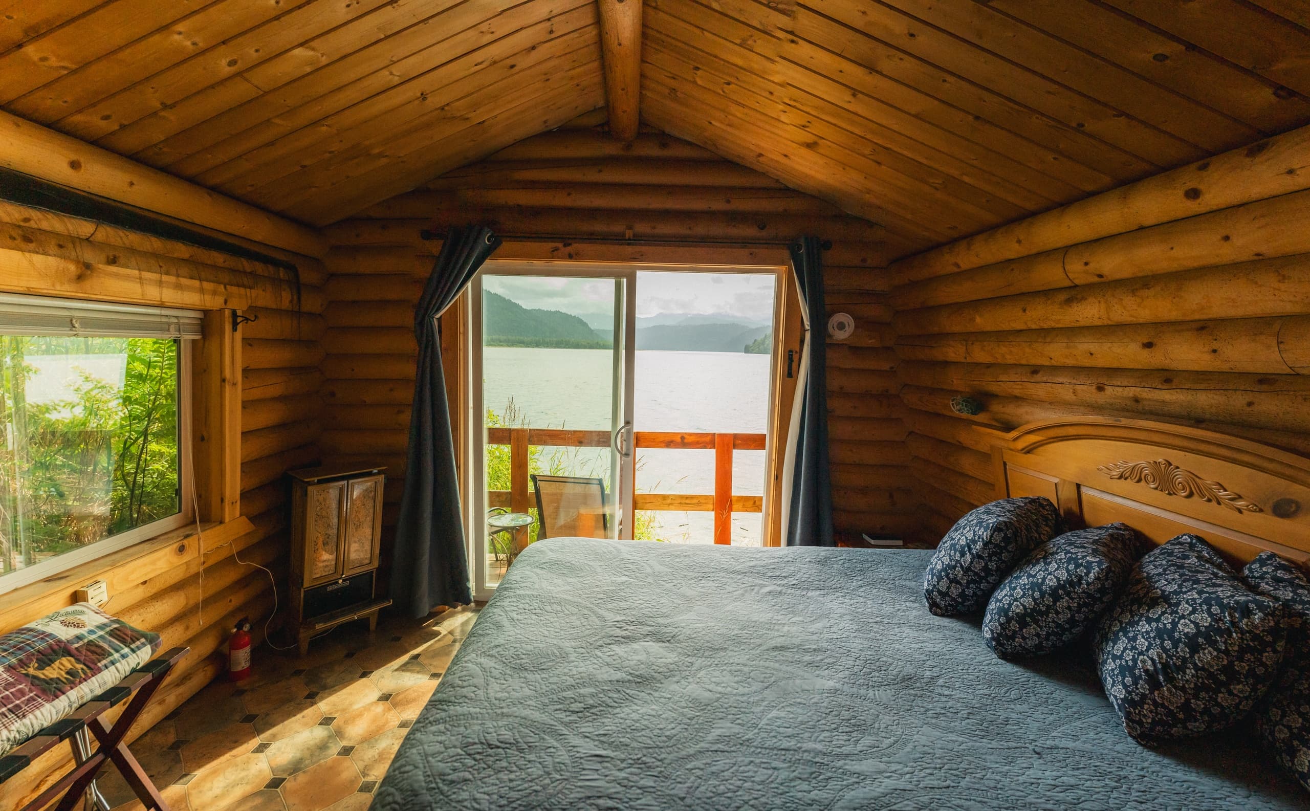 Cozy log cabin bedroom with lake view and sliding glass door