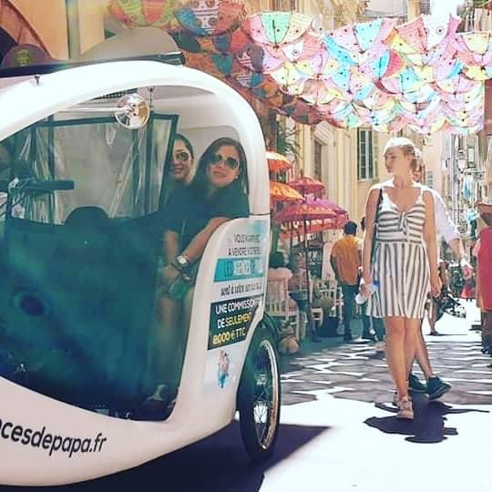 Pedicab moving through colorful pedestrian street market under umbrellas