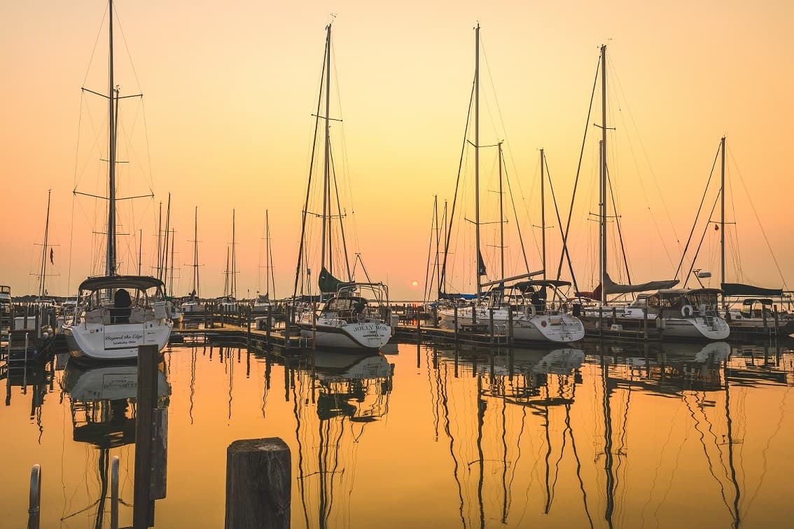 Sailboats moored at golden sunset in Lake Erie harbor reflection