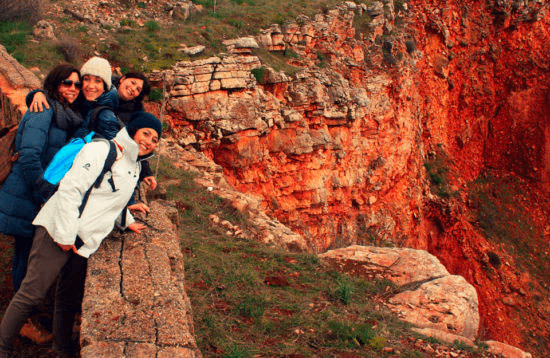 Hikers posing on rocky red-cliff overlook during canyon trek