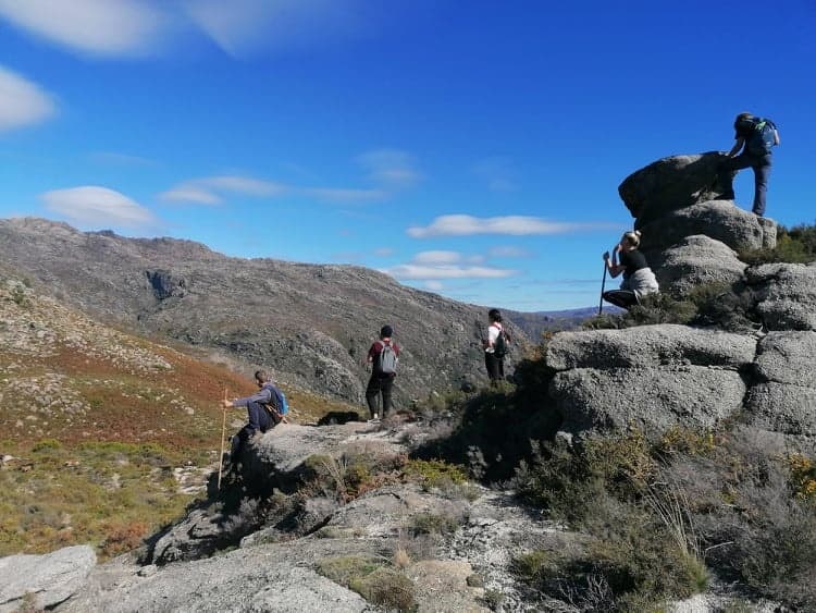 Hikers traversing rocky mountain ridge with panoramic blue sky