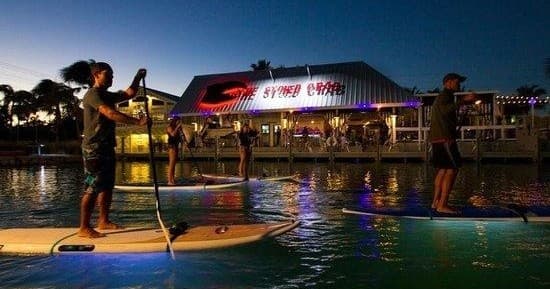 Evening paddleboarding near waterfront restaurants and lights