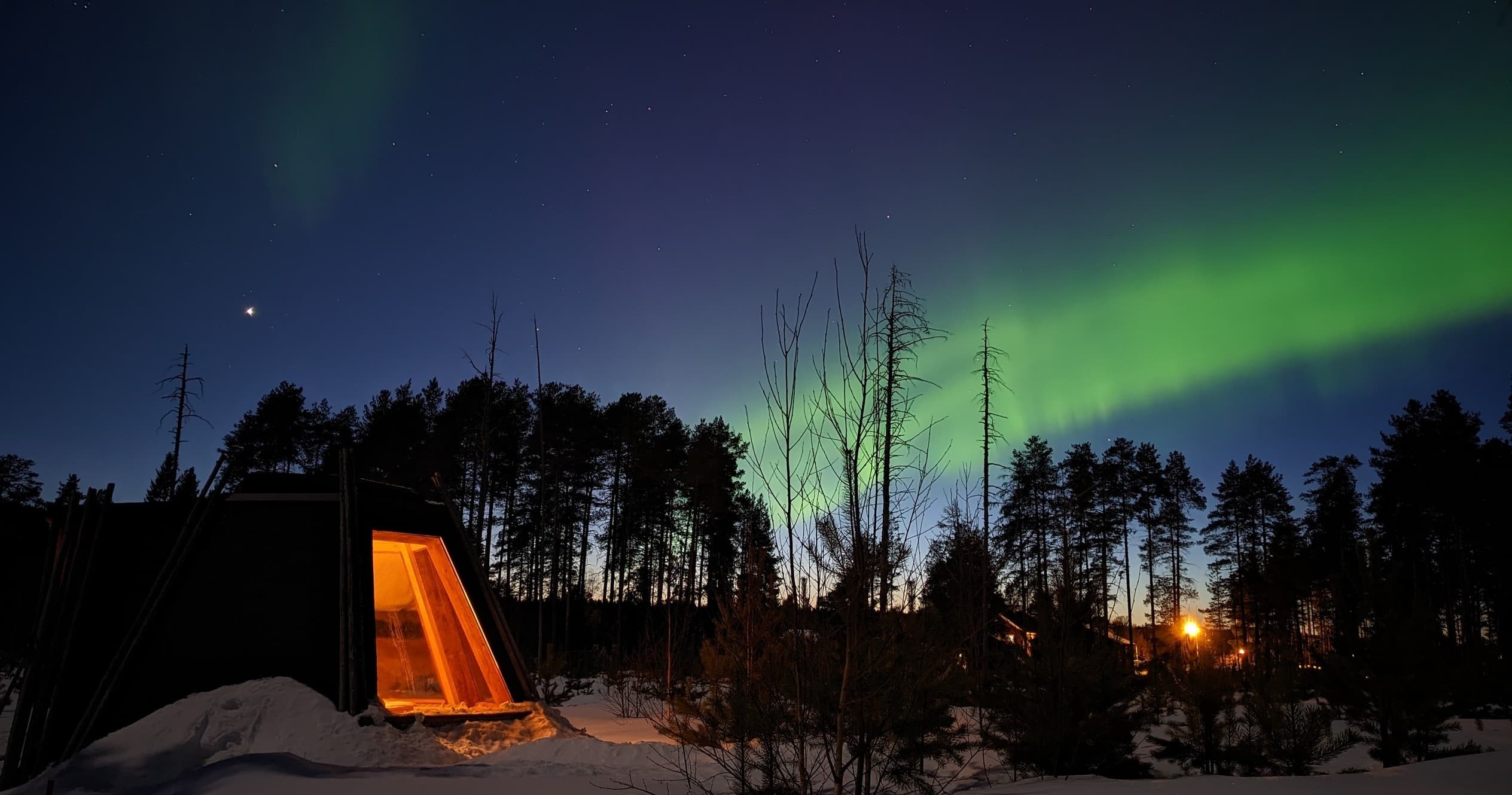 Cabin under northern lights in snowy forest camping experience