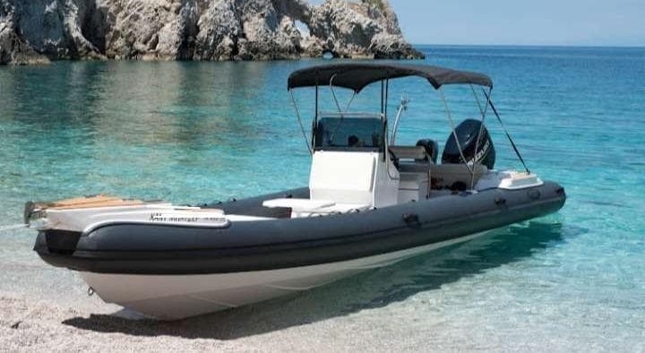 Rigid inflatable boat on turquoise coastal waters and rocky shore