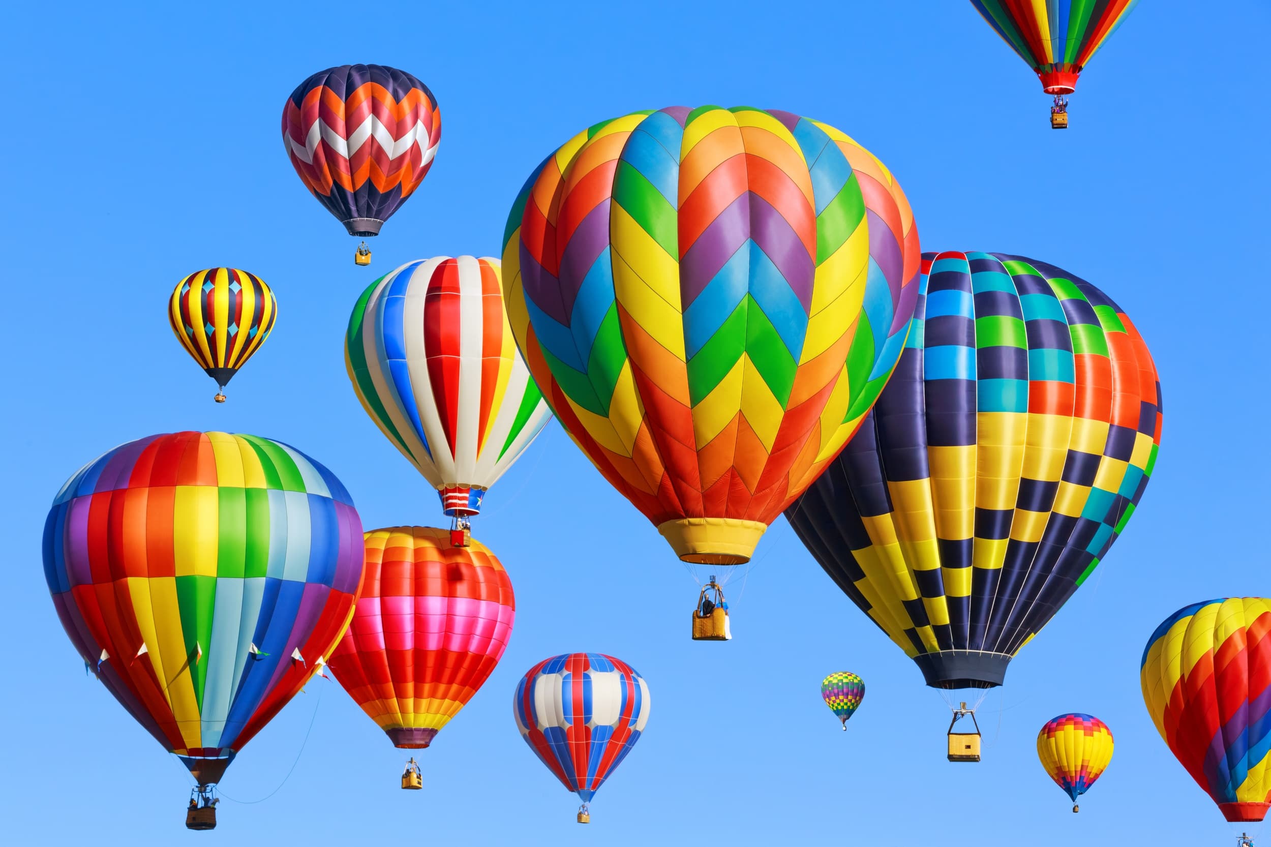 Colorful hot air balloons floating over bright blue sky festival