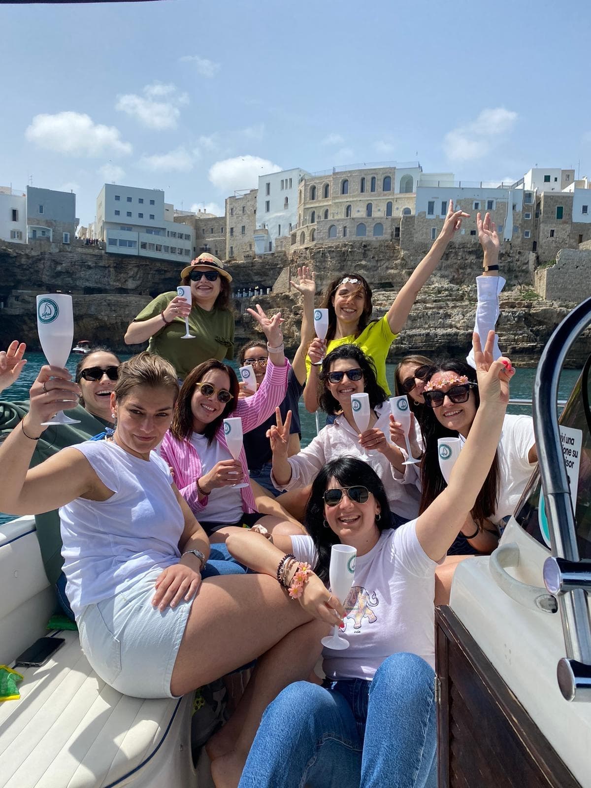 Group of friends celebrating on boat with coastal town backdrop