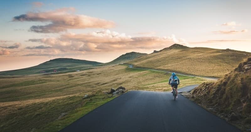 Cyclist riding on scenic mountain road at sunset