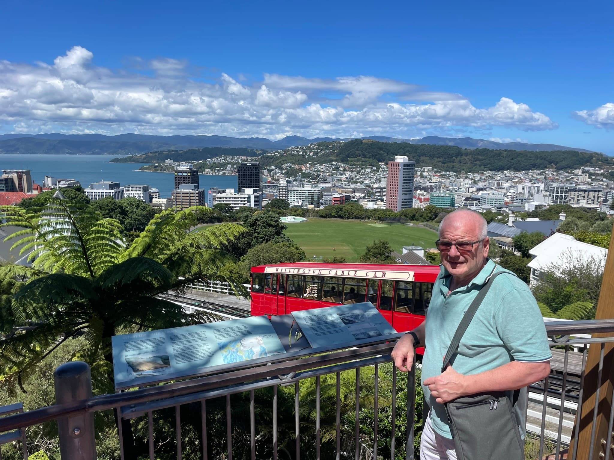Traveler at lookout with red cable car and city panoramas